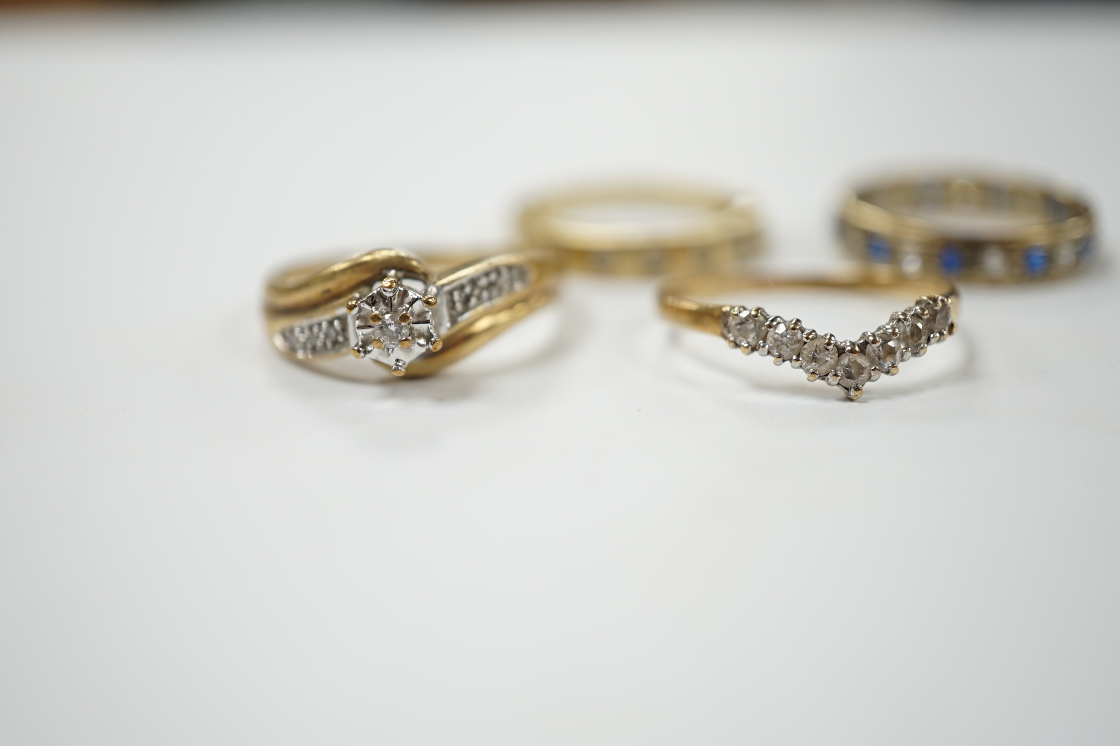 Two modern 9ct gold and diamond set rings and a 9ct gold, simulated diamond set chevron shaped ring and one other 9ct and paste set band, gross weight 9 grams. Condition - poor to fair